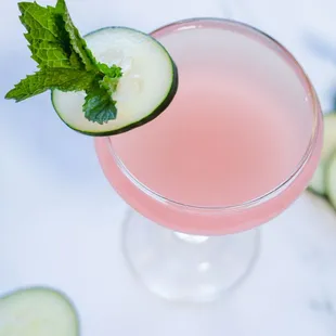 a pink cocktail with cucumber and mint
