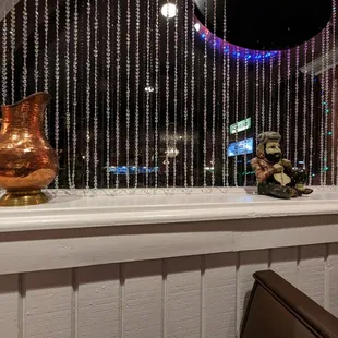 a gold pitcher and a teddy bear on a window sill