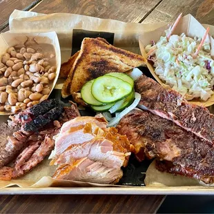 Three-meat plate with marbled brisket, turkey, ribs, pinto beans, coleslaw, Texas toast, and homemade pickles
