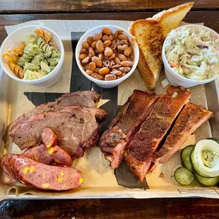 3-meat plate with prime marbled brisket, ribs, jalapeño-cheddar sausage, ranch pasta salad, pinto beans, coleslaw, TX toast, and pickles
