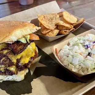 Double cheeseburger with bacon and sides of homemade chips and coleslaw. The burger is made with ground smoked prime brisket!