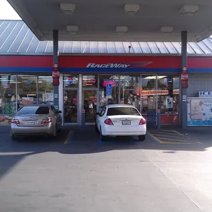 two cars parked in front of a gas station