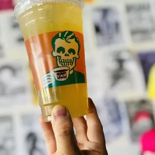 a hand holding a cup of orange juice