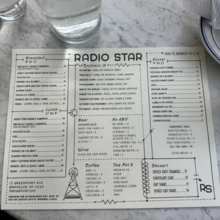 a menu on a table with a glass of water