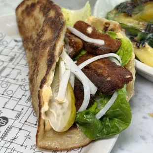 a sandwich on a plate with lettuce and onions