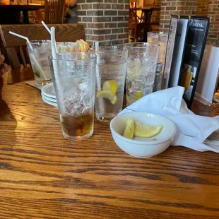 a wooden table with a bowl of ice tea and lemon slices