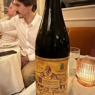a man sitting at a table with a bottle of wine