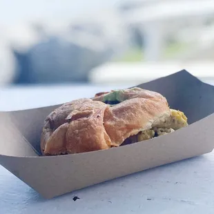 a croissant sandwich in a paper container
