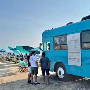 people standing in front of a blue bus