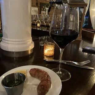 a glass of wine and a plate of sausages