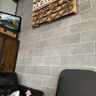 a brick wall with a wooden sign and a black leather chair