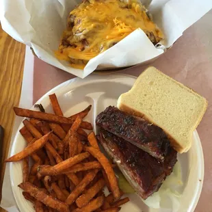 One meat plate with ribs and sweet potato fries and a baked potato with chopped beef
