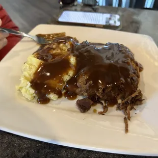 a plate of food with gravy and mashed potatoes