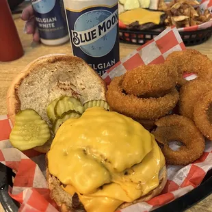 a burger and onion rings with a can of blue moon