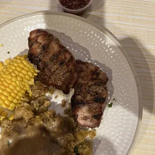 a plate of food with meat, rice and corn