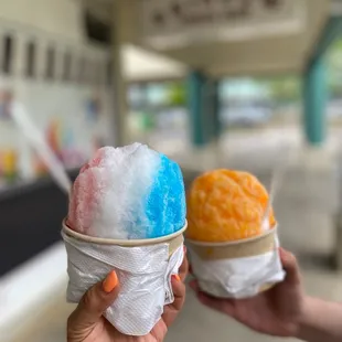 two hands holding two bowls of ice cream
