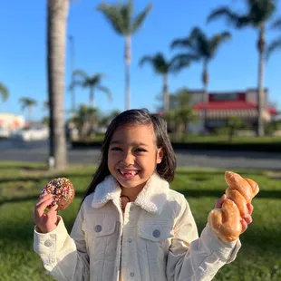 a little girl holding two donuts