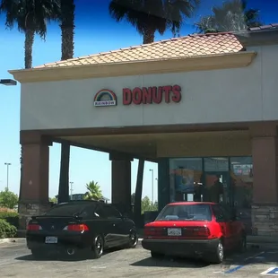 two cars parked in front of a donut shop