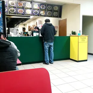 a man standing at the counter of a restaurant