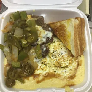 Custom breakfast plate with beef patty, gravy, bell peppers, onion, cheese eggs on top of grits... enjoy