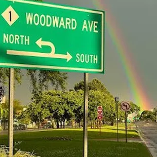 a rainbow in the distance and a street sign in the foreground