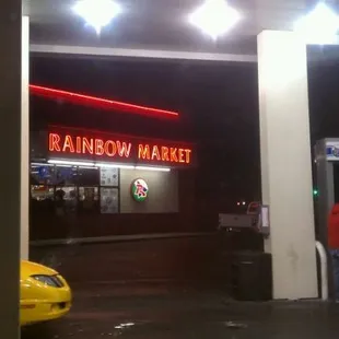 a yellow car in front of a neon sign