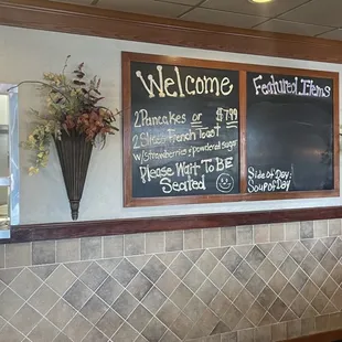 a restaurant counter with a menu on the wall