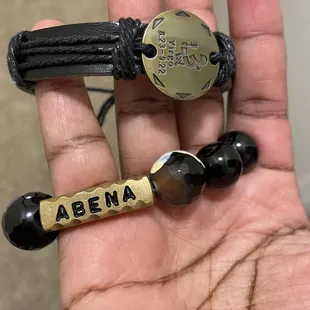 a person's hand holding two bracelets