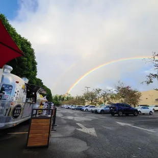 a rainbow in the sky over a parking lot