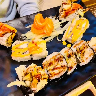 a variety of sushi on a black plate