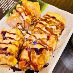 four pieces of sushi on a plate next to a cup of coffee