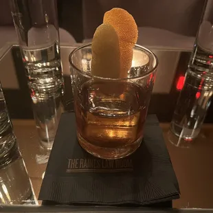 a drink in a glass with an orange peel