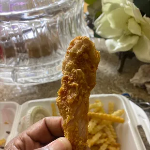 a hand holding a piece of fried chicken