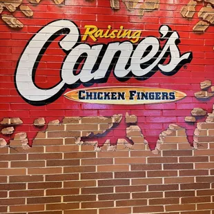 a brick wall with a sign that says raising cane's chicken fingers