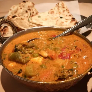 a bowl of vegetable curry with naan bread