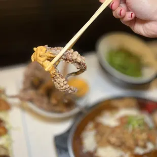 a person holding chopsticks over a bowl of rameki