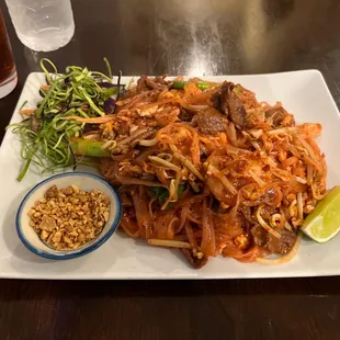 a plate of noodles with meat and vegetables