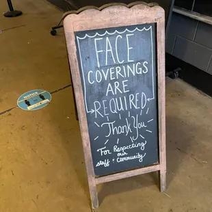 a chalk board with a sign that says face coverings are required thank you