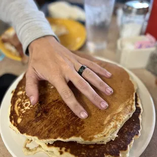 a person's hand on a stack of pancakes
