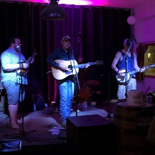 three men playing guitar and singing