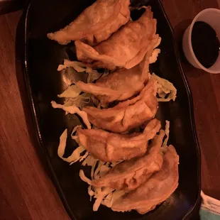 a plate of dumplings and a cup of sauce
