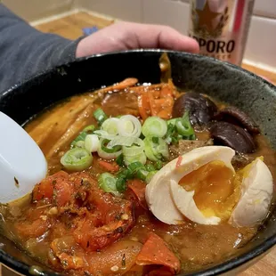 Veggie curry ramen topped with carrot, mushroom, fried tofu, and tomato, plus requested egg)