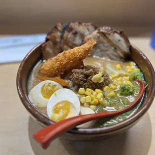 a bowl of ramen with meat, eggs, and corn