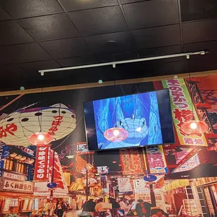 Wall mural and a tv that plays episodes of Naruto (it was muted or low volume).