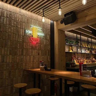 a bar with stools and a neon sign