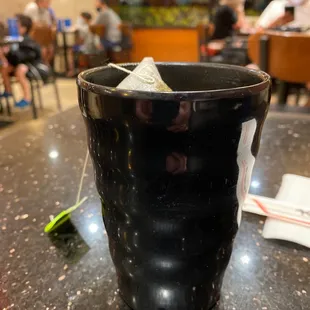 a black cup with a teabag in it