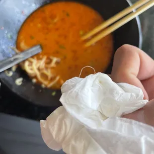 a person holding a bowl of ramen and chopsticks