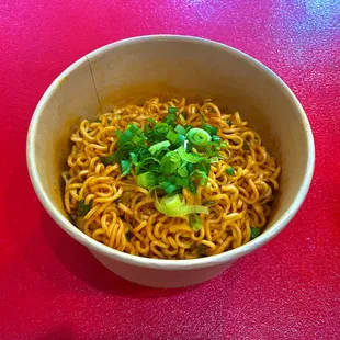 a bowl of ramen noodles on a red table