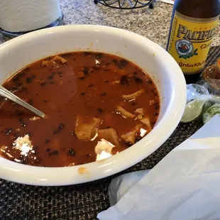 a bowl of soup and a bottle of beer