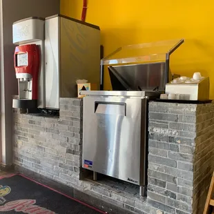 a kitchen area with a refrigerator, sink, and a coffee maker